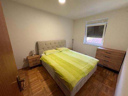 a bedroom with a bed with a yellow comforter and a window at Apartman Ana in Trebinje