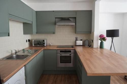 a kitchen with green cabinets and a wooden counter top at Garden flat seafront Hastings in Hastings