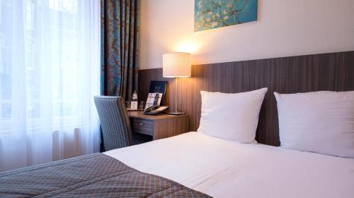 a bedroom with a bed and a desk with a lamp at Hotel Aalders in Amsterdam