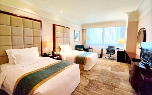 a hotel room with two beds and a desk at Grand Concordia Hotel in Beijing