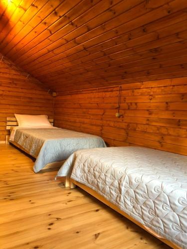 two beds in a room with wooden walls at ShodaView in Oni