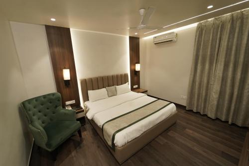 a bedroom with a bed and a green chair at MAG Hotels in Patna