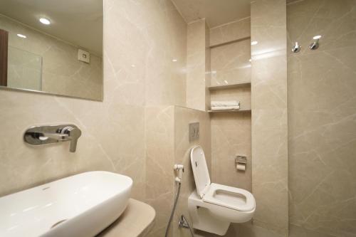 a bathroom with a white toilet and a sink at MAG Hotels in Patna