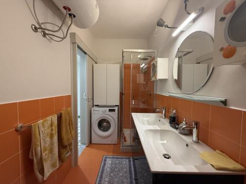 a bathroom with a sink and a washing machine at Capo d'Arco - Bougainvillea in Capo D'Arco