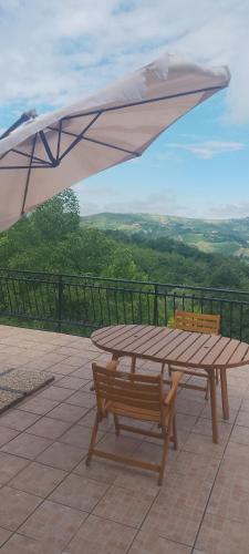 a wooden picnic table with an umbrella on a patio at B&B Cuccagna in Rocca deʼGiorgi