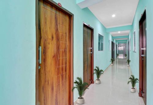 a hallway with blue walls and a wooden door and potted plants at Super Collection O The Kailash Hotel in Dehradun