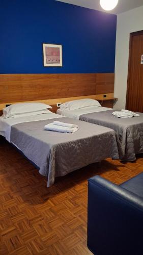 two beds in a room with a blue wall at Locanda El Piron in Chiampo