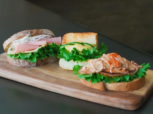 two sandwiches sitting on a wooden cutting board at Hotel Anteroom Kyoto in Kyoto