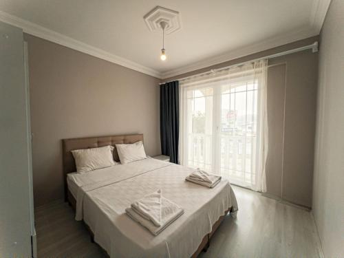 a bedroom with a bed with white sheets and a window at Ng Hisar Apart Hotel in Fethiye
