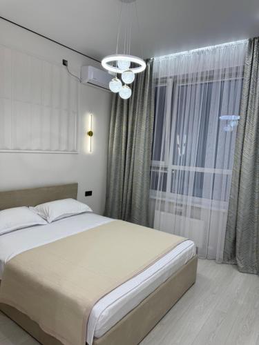 a bedroom with a bed and a large window at ЖК Ұлы Дала in Shymkent