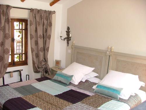 1 dormitorio con 1 cama con 2 almohadas y ventana en La Suite du Village d'Eze en Èze