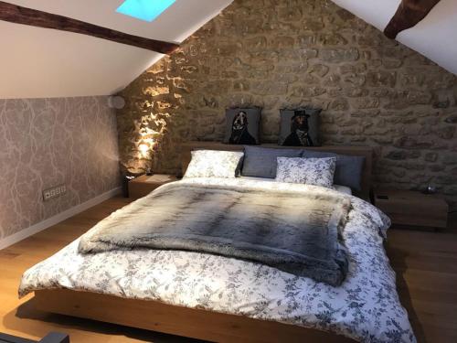a bedroom with a large bed with a stone wall at Le Pot de Miel d'Ugny in Ugny