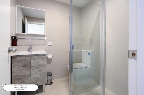 a bathroom with a shower and a toilet and a sink at Surf Beach Motel Newcastle in Newcastle