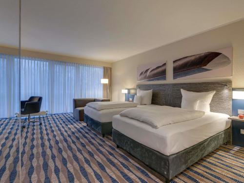 a hotel room with two beds and a desk at Mercure Hotel am Entenfang Hannover in Hannover