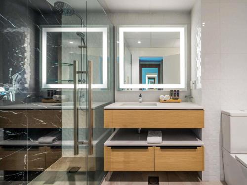 a bathroom with a sink and a glass shower at Novotel Tainui Hamilton in Hamilton
