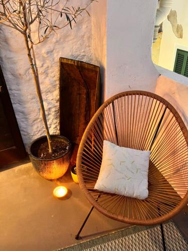 a rattan chair with a pillow next to a plant at Charming Casa Maria Pag in Pag
