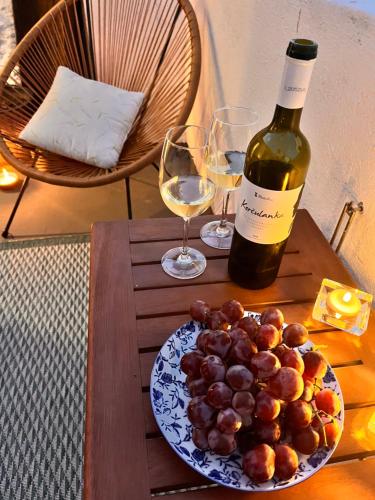 a table with a bottle of wine and a plate of grapes at Charming Casa Maria Pag in Pag
