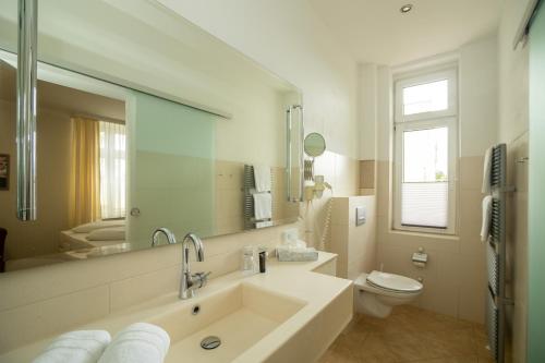 a bathroom with a sink and a toilet and a mirror at Hotel Union Salzwedel in Salzwedel