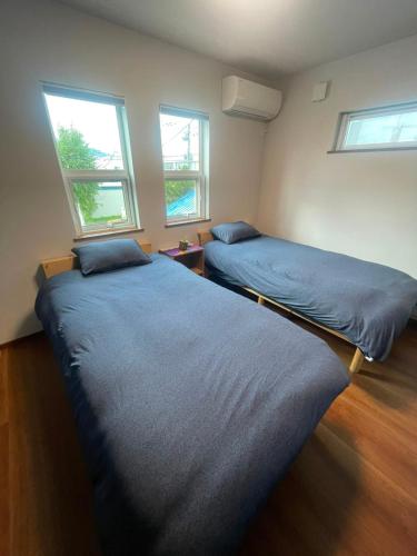 two beds in a room with two windows at Hotel Ji ホテル時 in Furano