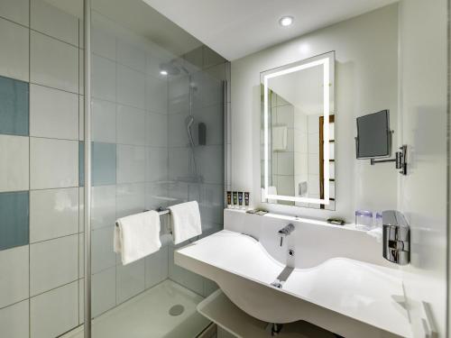 a white bathroom with a sink and a mirror at Novotel Zurich City West in Zurich