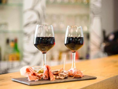 two glasses of wine and meat on a table at ibis Rodez Centre in Rodez