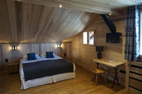 a bedroom with a bed and a table and a television at Maison d'hôtes La Barmaz in Combloux