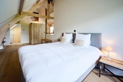 a bedroom with a large white bed and a table at Muntershof in Zottegem