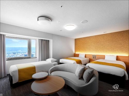 a hotel room with three beds and a couch at Daiwa Roynet Hotel Wakayama in Wakayama