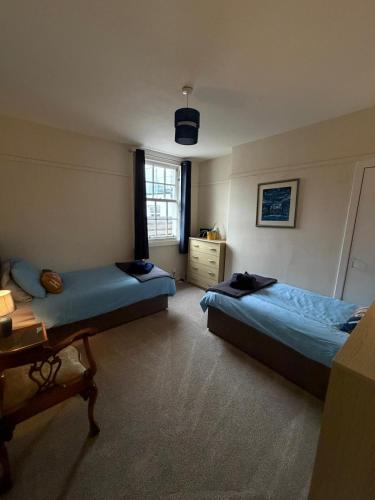 a bedroom with two beds and a table and a window at Papa Jim's Cottage in Dirleton
