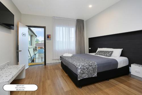 a bedroom with a large bed and a balcony at Surf Beach Motel Port in Port Macquarie