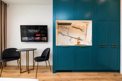 a room with blue cabinets and a table and chairs at GreenRoom Kunigiškės in Palanga