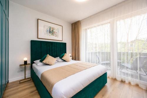 a bedroom with a large bed and a large window at GreenRoom Kunigiškės in Palanga