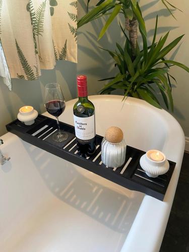 a bottle of wine and a glass in a bath tub at Welsh Yard Retreat in Penrith