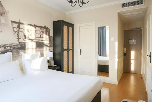 a white bedroom with a bed and a bathroom at Best Western Le Cheval Blanc -Vue sur le port-plein centre ville in Honfleur