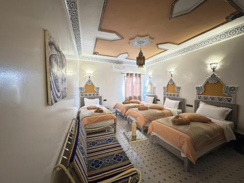 a bedroom with four beds in a room at Riad Dar Fatima in Merzouga