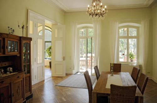 a dining room with a table and chairs and a chandelier at Gutshaus Alt Vorwerk in Boddin