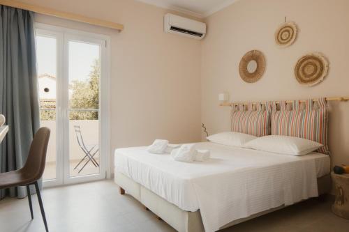 a white bedroom with a bed and a balcony at Cavo Notos Beach Hotel in Kavos