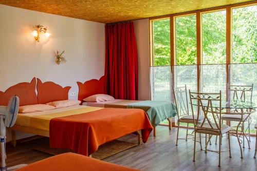a room with two beds and a table and chairs at Hotel Rose in Beauvoir