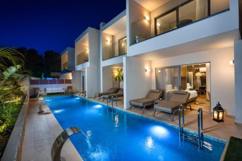 a villa with a swimming pool at night at Oasis Luxury Suites in Kolymbia