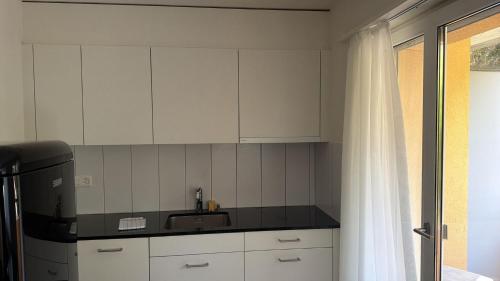 a kitchen with white cabinets and a black counter top at Swiss Star District 11 - Self Check-In in Zurich