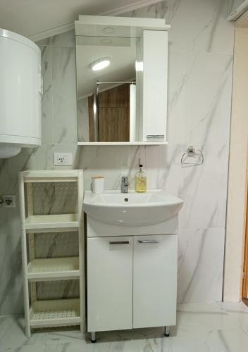 a white bathroom with a sink and a mirror at Sobe Išić in Veliko Gradište