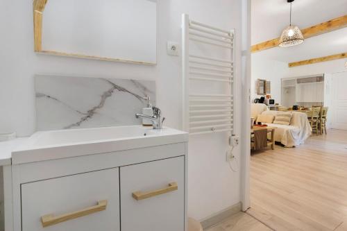 a white bathroom with a sink and a mirror at Suite Maraval Chez L'habitant in Trélissac