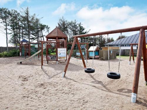a playground with a swing set in the sand at Blokhus Feriecenter in Blokhus