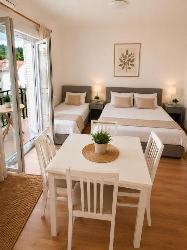 a bedroom with two beds and a table and chairs at Apartments Butkovic in Hvar