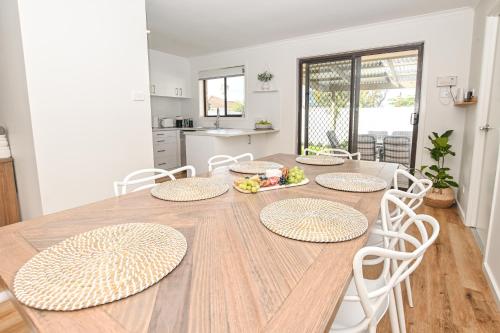 a dining room table with white chairs and a kitchen at Kingscote Getaway Kangaroo Island in Kingscote