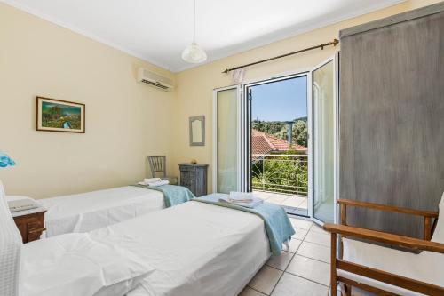 two beds in a room with a view of a balcony at VK Villas in Apolpaina