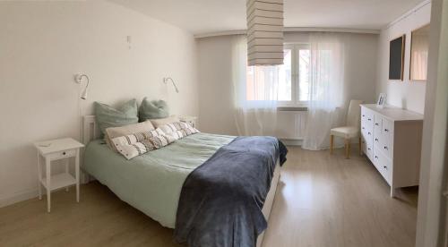 a white bedroom with a large bed and a window at Zur Streuobstwiese in Storndorf