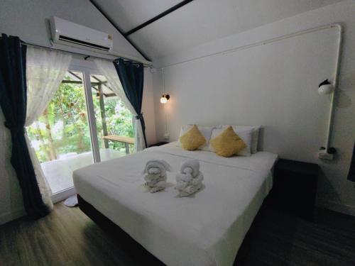 a bedroom with a bed with two stuffed animals on it at น้ำหราธาราโฮมสเตย์ in Ban Thung Nui