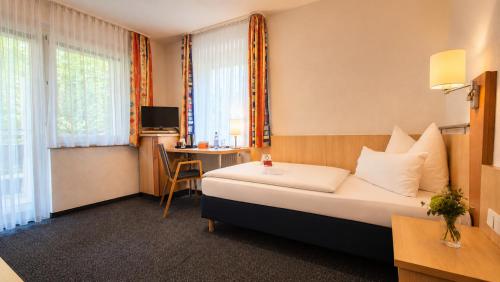 a hotel room with a bed and a desk at Tagungszentrum Neuendettelsau in Neuendettelsau