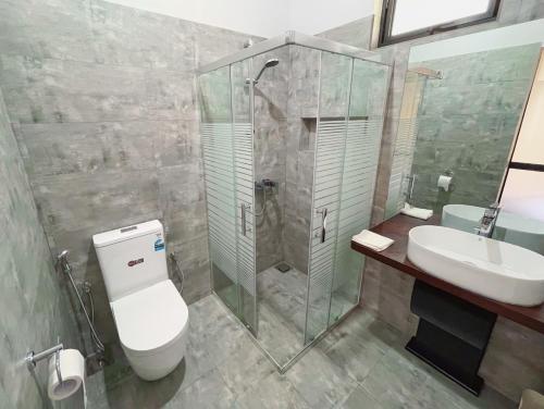 a bathroom with a shower and a toilet and a sink at Yala Hideaway in Tissamaharama